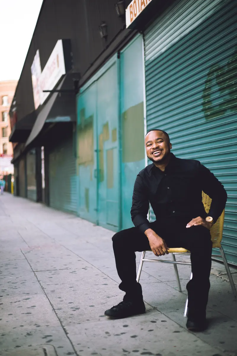 Tierre Maclin smiling in front of a storefront, photographed by 12pastseven